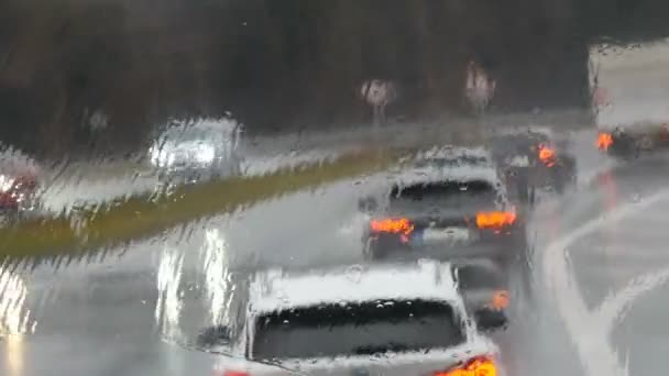 Vista do engarrafamento na estrada durante a chuva. Os carros vão em fila. Tiro de gotas de chuva e estrias na janela od ônibus em movimento em um outono profundo — Vídeo de Stock