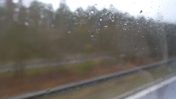 Γκρο πλαν βολή της βροχής πέφτει και ραβδώσεις στο παράθυρο od κινούμενο λεωφορείο από την πόλη δρόμου σε βάθος το φθινόπωρο — Αρχείο Βίντεο