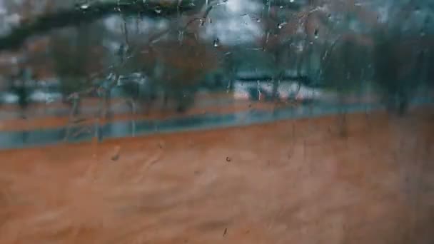 Primo piano di gocce di pioggia e striature sul finestrino di autobus in movimento per la strada della città in autunno profondo — Video Stock