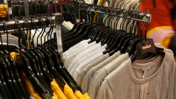 Nuremberg, Alemania - 3 de diciembre de 2018: Varias prendas colgadas de perchas negras de moda en una tienda de ropa en un centro comercial o centro comercial — Vídeos de Stock