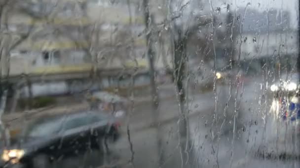 Primer plano de gotas de lluvia y rayas en la ventana od autobús en movimiento por la calle de la ciudad en otoño profundo — Vídeo de stock
