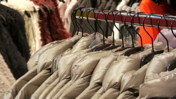Verschiedene Frauen Winterjacken Kleidung hängen an Kleiderbügeln in einem Bekleidungsgeschäft in Einkaufszentrum oder Einkaufszentrum — Stockvideo