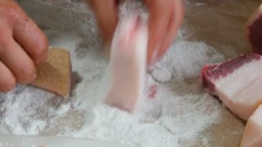 Erkek kasap büyük domuz parçalarını yağla, derisini de tuzla kaplar.
