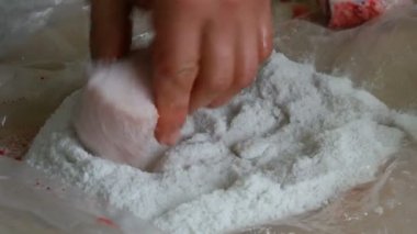 Erkek kasap büyük domuz parçalarını yağla, derisini de tuzla kaplar.