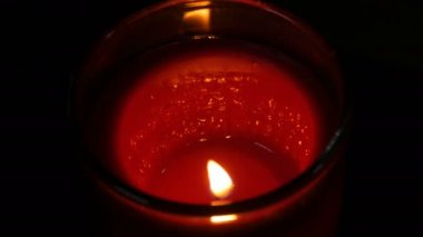 Karanlıkta büyük yuvarlak kırmızı memorial mum yakıyor. Siyah bir arka plan üzerine de mum alevi