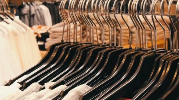 Um grande número de roupas femininas de cores diferentes paira sobre cabides e fica nas prateleiras em uma loja de roupas do centro comercial ou shopping. O problema do consumismo — Vídeo de Stock