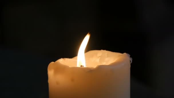 Grande bougie blanche de cire brûle et se tient sur fond noir dans une vieille église médiévale en Allemagne . — Video