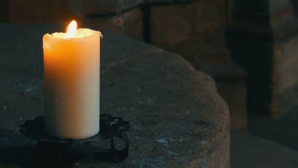 Große wachsweiße Kerze brennt und steht in einem alten Kerzenständer in einer mittelalterlichen Kirche in Deutschland. — Stockvideo