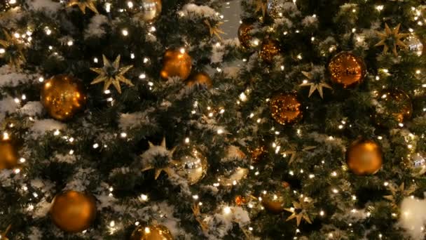 Árbol de Navidad bellamente decorado con grandes bolas de oro y plata, estrellas, guirnaldas y nieve artificial está de pie en el centro comercial vista de cerca — Vídeo de stock