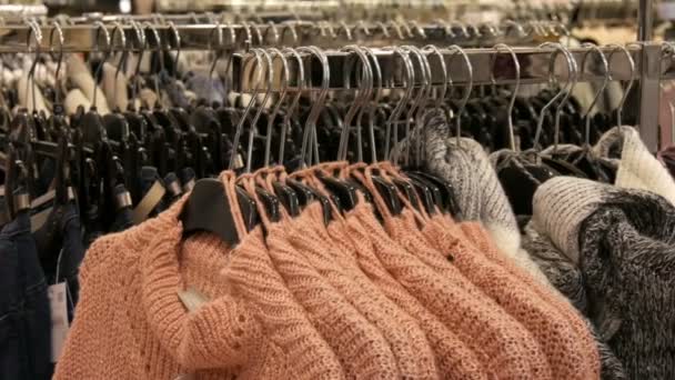Norimberk, Německo – 1. prosince 2018: Velký počet nových teplé stylové svetry různých barev, visí na ramínkách v oblečení obchod obchodní centrum nebo mall — Stock video