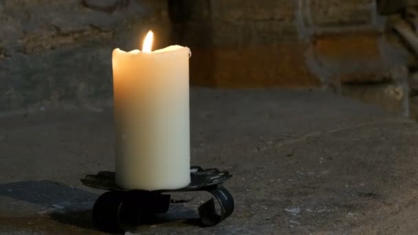 große wachsweiße Kerze brennt und steht in einem alten Kerzenständer in einer mittelalterlichen Kirche in Deutschland.