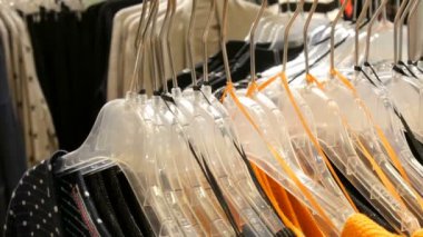 Şık elbise askıları bir alışveriş merkezinde bir giyim mağazası satırındaki asılı.