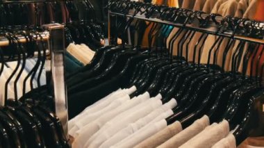 Şık elbise askıları bir alışveriş merkezinde bir giyim mağazası satırındaki asılı.