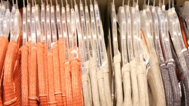 Stylové šaty visí v řadě na ramínkách v obchodě s oděvy v obchoďáku. — Stock video