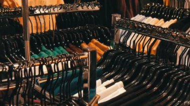 Şık elbise askıları bir alışveriş merkezinde bir giyim mağazası satırındaki asılı.