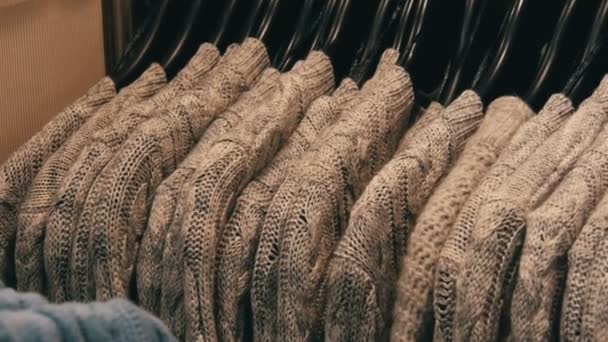 Fashionable youth clothes hanging on hangers in a clothing store in a shopping center. — Stock Video