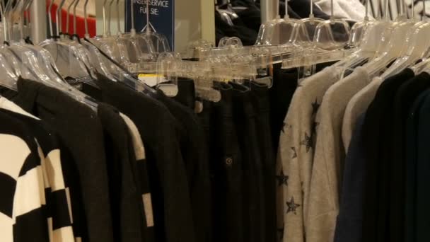 Ropa elegante colgando en fila en perchas en una tienda de ropa en un centro comercial . — Vídeos de Stock