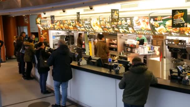 Munich, Germany - December 2, 2018: The queue of people who stay before the counter and want to buy food at the famous fast food McDonalds in Karlsplatz Stachus. — Stock Video