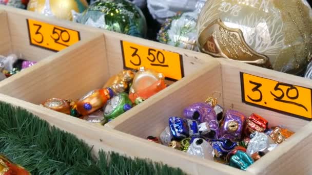 Verschiedene schöne Weihnachtskugeln und Spielsachen schmücken die Weihnachtstanne auf der Markttheke. Inschrift in deutscher Sprache — Stockvideo