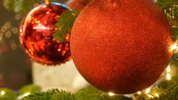 Belas bolas de brinquedo de árvore de Natal elegantes de cor vermelha paira na árvore de Natal vista de perto. Ano Novo e decoração de Natal . — Vídeo de Stock