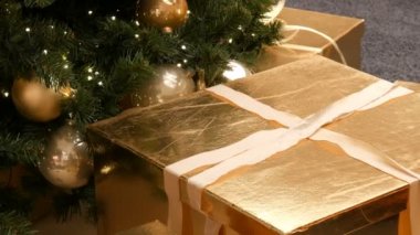 Büyük hediye kutuları, alışveriş merkezindeki Noel ağacının altında altın rengi mevcut. Noel ve yeni yıl hediye dekor. Altın saten kurdele ile altın hediye kutusu.