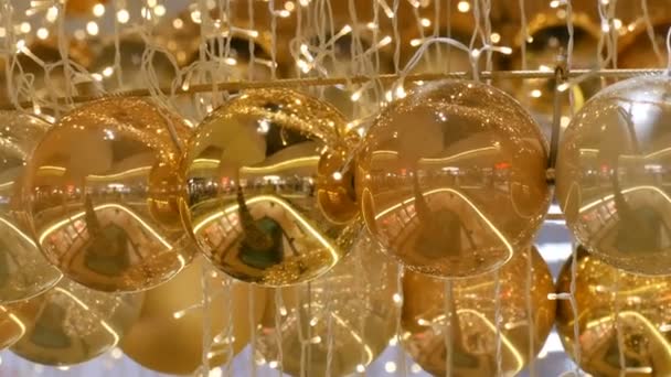 Ghirlande di Natale luci e palle di colore oro con uno sfondo sfocato. Capodanno e decorazioni natalizie nel centro commerciale . — Video Stock