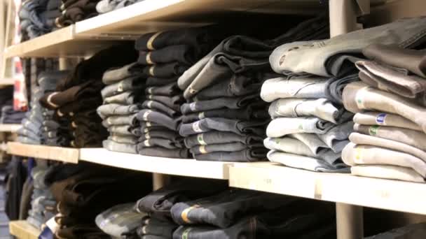 Norimberk, Německo – 3. prosince 2018: Obrovské pult s policemi na kterém leží v řadě složen trendy džíny. Jeans store v obchoďáku. — Stock video