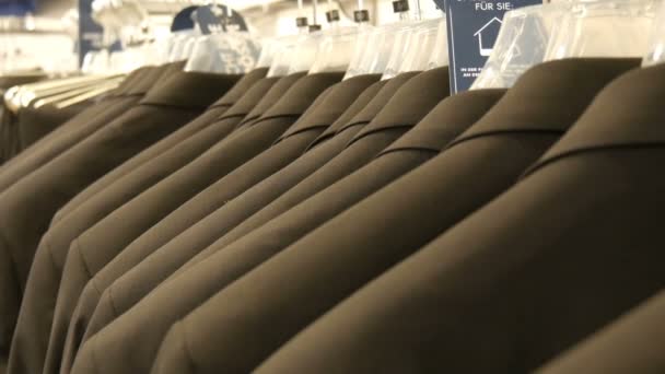 Aantal identieke-gekleurde mens past opknoping op een hanger in een kledingwinkel in een winkelcentrum — Stockvideo