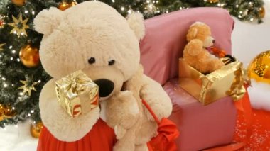 Beyaz oyuncak ayı, tutan bir hediye olarak onun pençeleri ile bir kutu ve hamle Noel ağacı arka plan üzerinde görünümü kapatın. Alışveriş merkezindeki Noel dekor