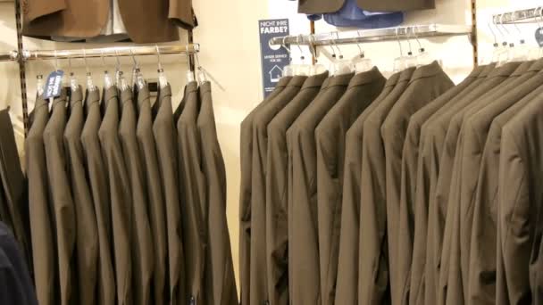 Antal identiska-färgade mens passar hänger på en galge i en klädaffär i ett köpcentrum — Stockvideo