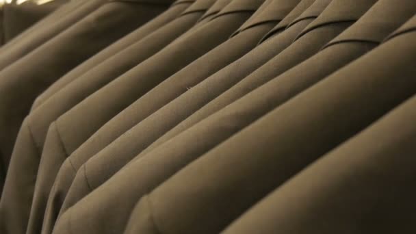 Αριθμός mens πανομοιότυπα-χρωματισμένα κοστούμια κρέμεται σε μια κρεμάστρα σε ένα κατάστημα ιματισμού σε ένα εμπορικό κέντρο — Αρχείο Βίντεο