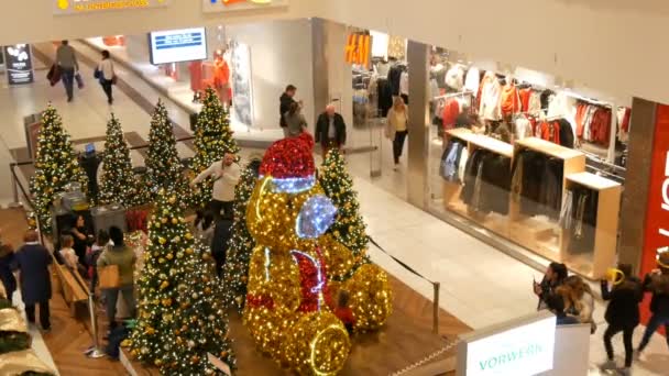 Núremberg, Alemania - 1 de diciembre de 2018: árboles de Navidad decorados con grandes bolas de oro y plata, estrellas, guirnaldas y nieve artificial y oso grande están en el centro comercial con compradores ambulantes — Vídeo de stock