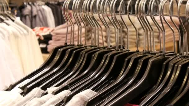 Um grande número de roupas femininas de cores diferentes paira sobre cabides e fica nas prateleiras em uma loja de roupas do centro comercial ou shopping. O problema do consumismo — Vídeo de Stock