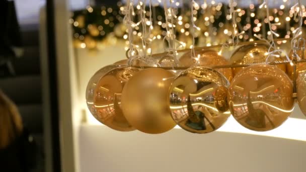 Jul kransar lampor och bollar av guld färg med en suddig bakgrund. Nyår och jul inredning i gallerian shopping center. — Stockvideo