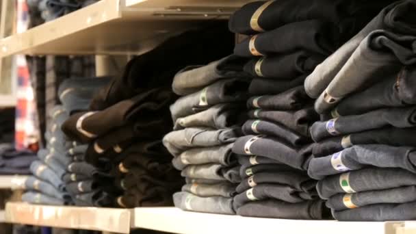 Norimberk, Německo – 3. prosince 2018: Obrovské pult s policemi na kterém leží v řadě složen trendy džíny. Jeans store v obchoďáku. — Stock video