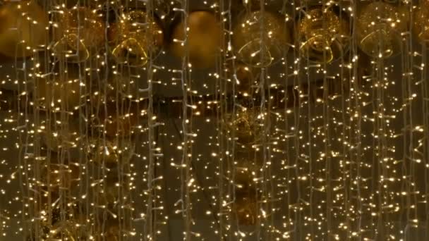 Jul kransar lampor och bollar av guld färg med en suddig bakgrund. Nyår och jul inredning i gallerian shopping center. — Stockvideo