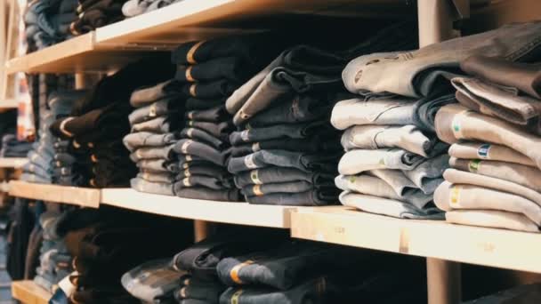Nürnberg, Duitsland - 3 December 2018: Een enorme teller met planken op welke leugen in een trendy jeans van rij gevouwen. Jeans store in het winkelcentrum. — Stockvideo