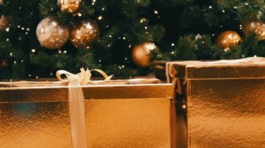 Büyük hediye kutuları, alışveriş merkezindeki Noel ağacının altında altın rengi mevcut. Noel ve yeni yıl hediye dekor. Altın saten kurdele ile altın hediye kutusu.