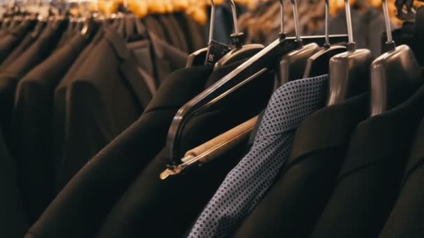 Una serie de chaquetas y camisas negras de moda para hombre diferentes en la percha en la tienda de ropa para hombre en el centro comercial . — Vídeo de stock