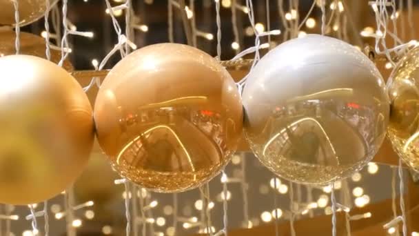 Рождественские гирлянды огни и шары золотого цвета с размытым фоном. Новогодний и рождественский декор в торговом центре . — стоковое видео