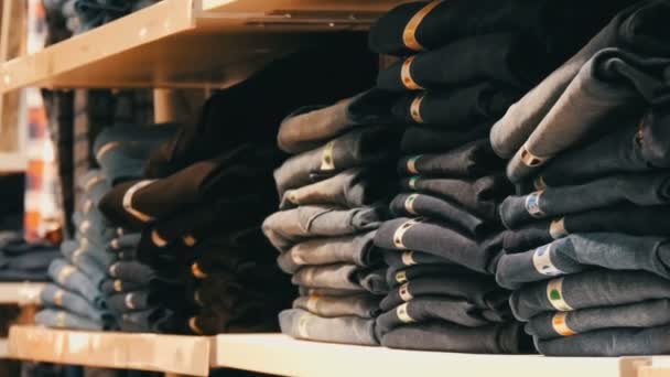 Нюрнберг, Германия - 3 декабря 2018 года: огромный прилавок с полками, на которых лежат рядами сложенные модные джинсы. Магазин джинсов в торговом центре . — стоковое видео