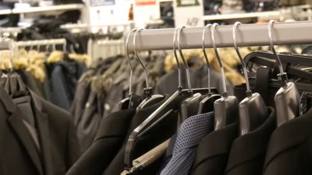 A number of different fashionable mens black jackets and shirts on the hanger in the mens clothing store in the shopping center. — Stock Video