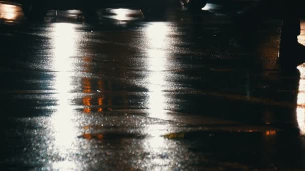 Piétons pieds traversant la rue la nuit et la pluie avec des fusées éclairantes frappant camer en arrière-plan. Vie urbaine . — Video