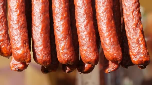 Una fila de salchichas ahumadas cuelgan de la vitrina de una carnicería — Vídeos de Stock