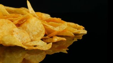 Patates cips rasgele siyah bir arka planda dağılmış bir ayna yüzeyi üzerinde yatıyor. Zararlı yiyecekler, Fast Food