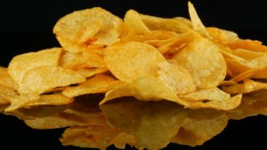 Patates cips rasgele siyah bir arka planda dağılmış bir ayna yüzeyi üzerinde yatıyor. Zararlı yiyecekler, Fast Food