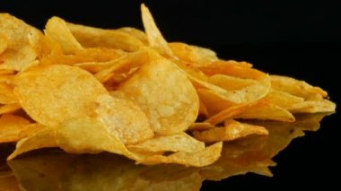 Patates cips rasgele siyah bir arka planda dağılmış bir ayna yüzeyi üzerinde yatıyor. Zararlı yiyecekler, Fast Food