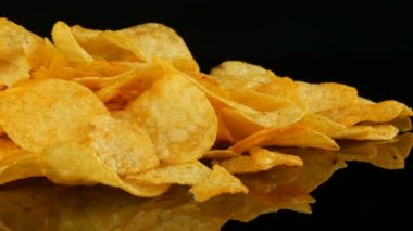 Kadın eller patates cips rastgele siyah bir arka planda dağınık bir ayna yüzeyi üzerinde yalan almak. Zararlı yiyecekler, Fast Food