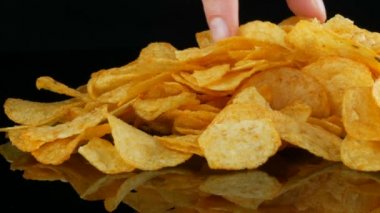 Patates cips rasgele siyah bir arka planda dağılmış bir ayna yüzeyi üzerinde yatıyor. Zararlı yiyecekler, Fast Food