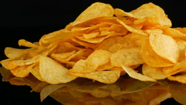 Burgonya chips hazugság a tükör felszínén véletlenszerűen szétszórva a fekete háttér. Ártalmas ételek, gyorséttermek — Stock videók